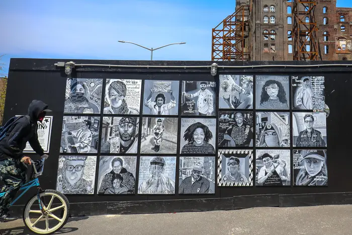 A wall of paintings outdoors portraying essential workers